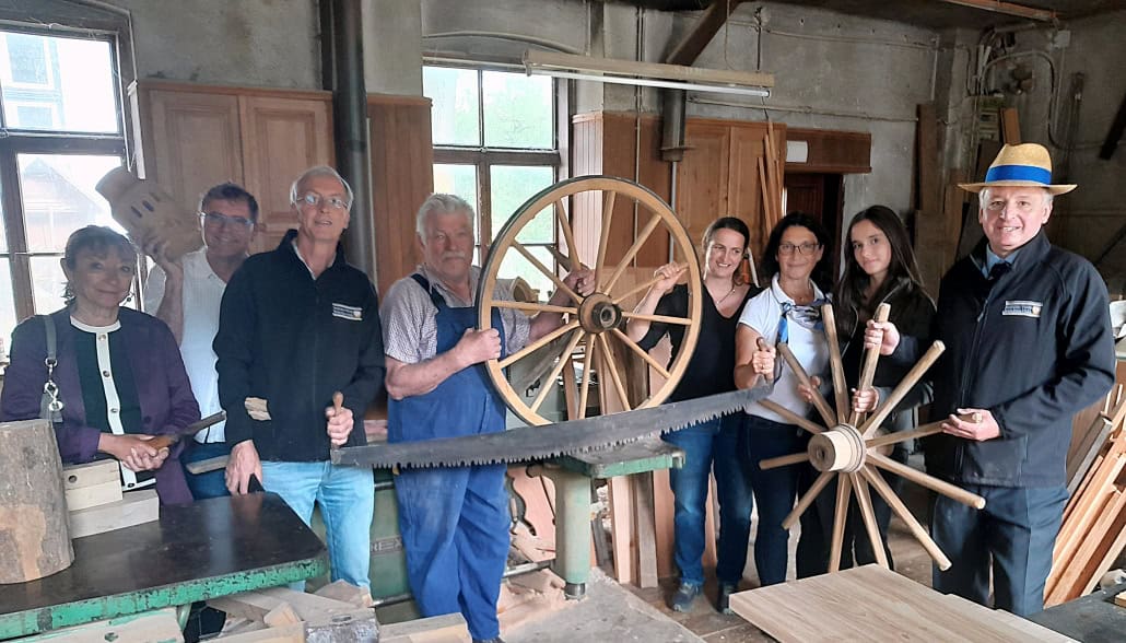 Reitkultur-Verein Weiß-Blau-Gold, Vereinsausflug am 30. August 2025, Besichtigung der Wagnerei Siegfried KONRAD in Kaumberg. Wagnermeister KONRAD mit Wagenrad (vierter von links im Bild) und Schatzmeisterin Karin Aschauer mit einem über 100 Jahre alten Wagnerwerkzeug (erste von links im Bild). © Reitkultur-Verein Weiß-Blau-Gold
